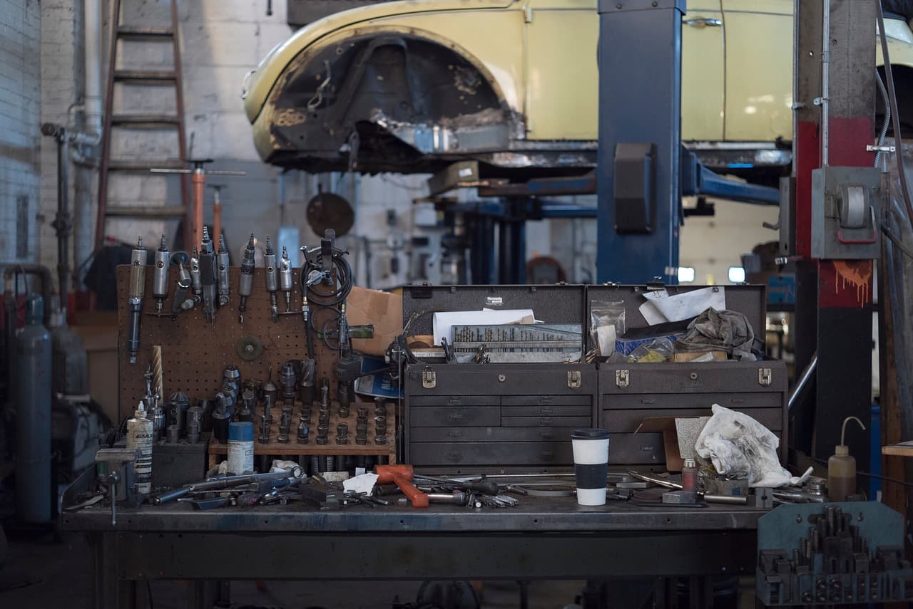 A workshop bench of tools with a car raised on the lift behind